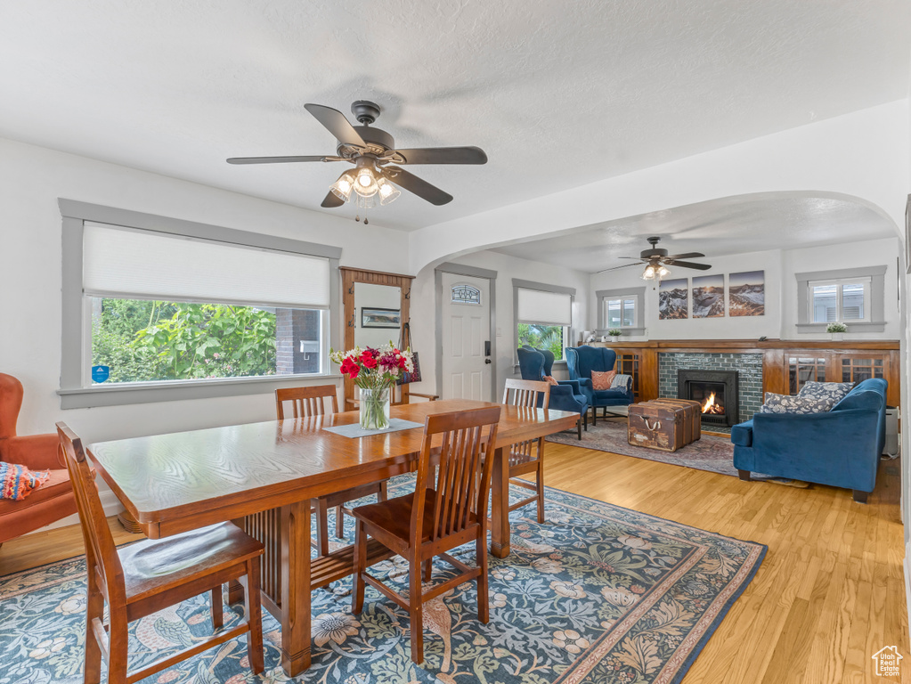 Dining space with arched walkways, ceiling fan, plenty of natural light, and light wood-style flooring