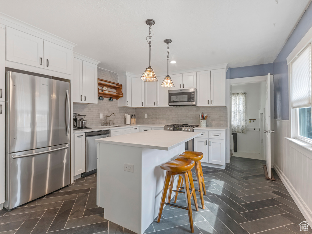 Kitchen with stainless steel appliances, white cabinets, and light countertops