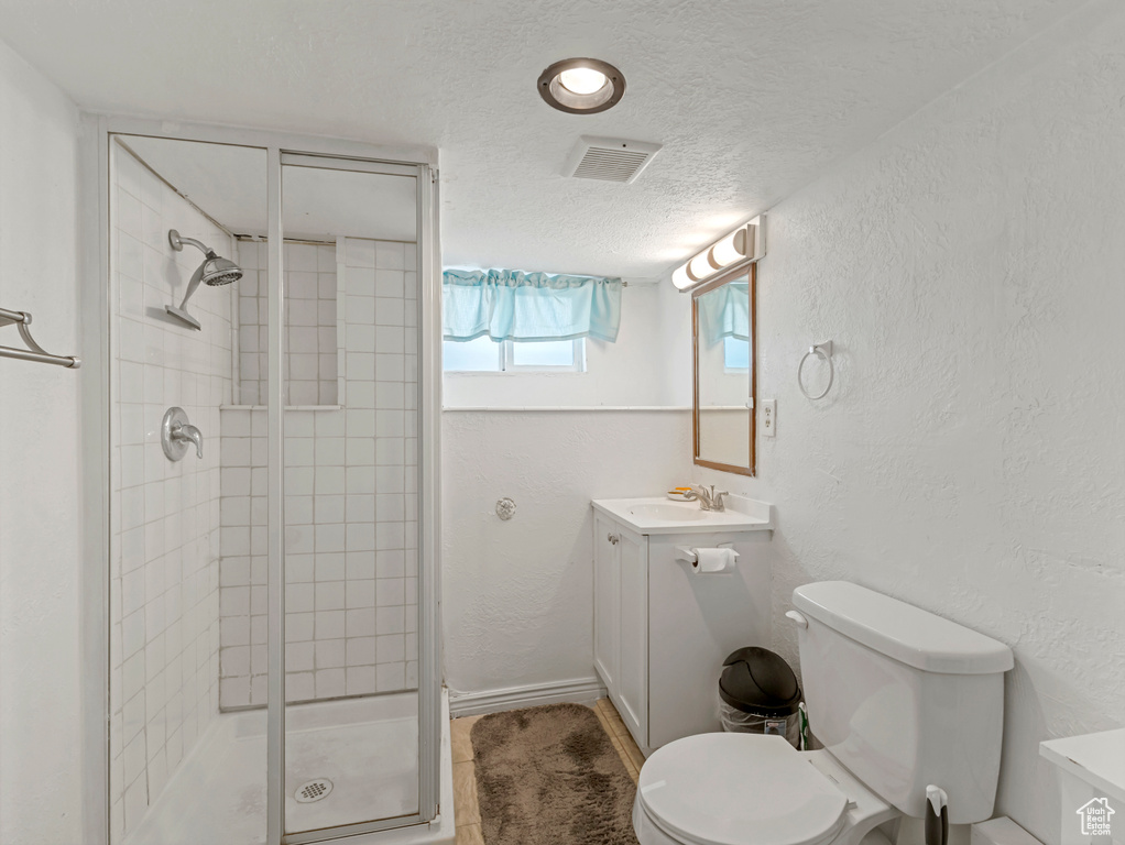 Full bath featuring vanity, a stall shower, a textured wall, and a textured ceiling