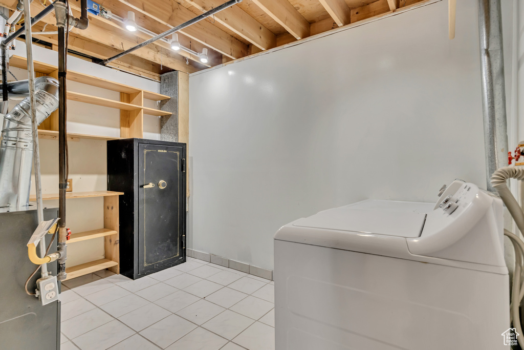 Laundry room featuring washing machine and dryer, light tile patterned floors, and a dry bar