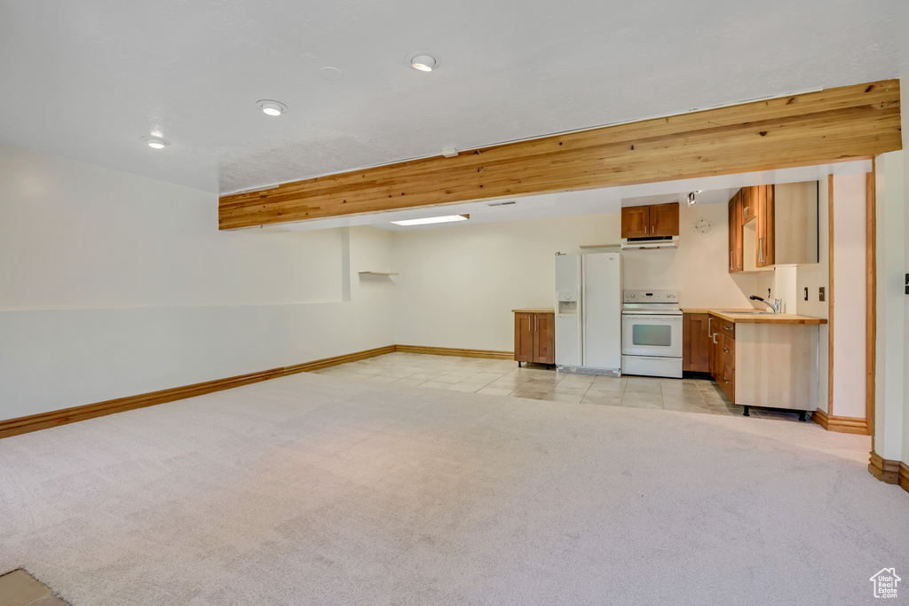 Finished basement with white fridge with ice dispenser, light carpet, and recessed lighting