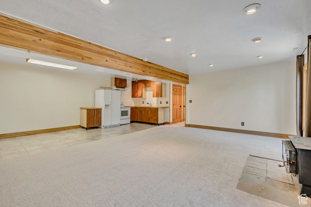 Unfurnished living room featuring recessed lighting, light colored carpet, and a wood stove