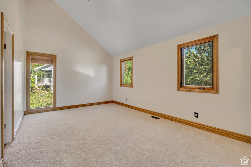 Spare room with light carpet and high vaulted ceiling