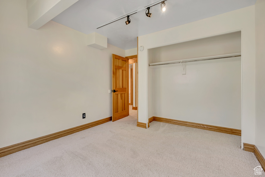 Unfurnished bedroom featuring carpet floors, a closet, and rail lighting