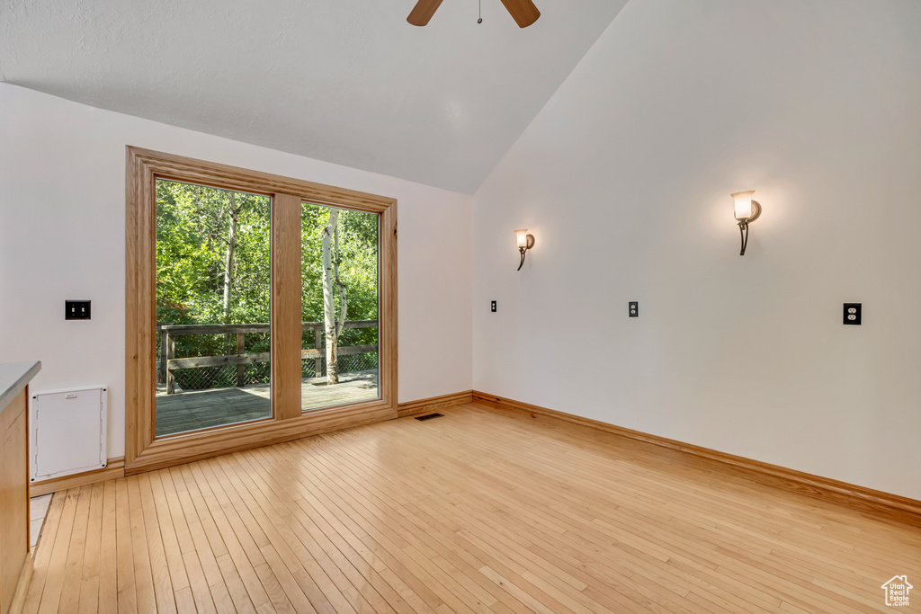 Empty room featuring light wood finished floors, ceiling fan, and high vaulted ceiling