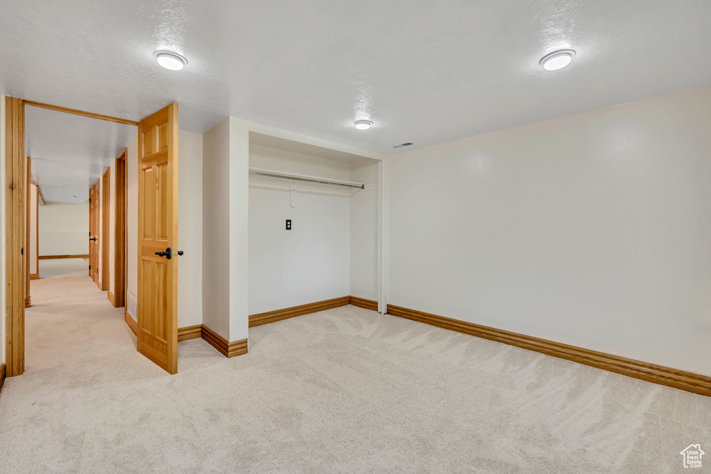 Unfurnished bedroom with light colored carpet and a closet