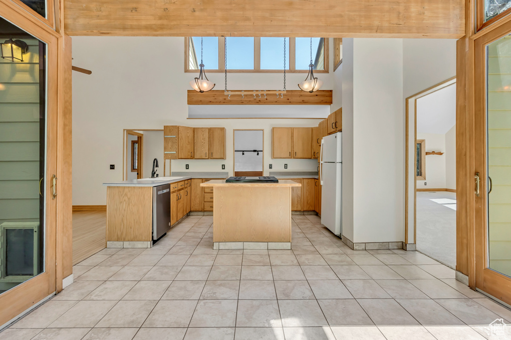 Kitchen featuring freestanding refrigerator, stainless steel dishwasher, a peninsula, light countertops, and a high ceiling