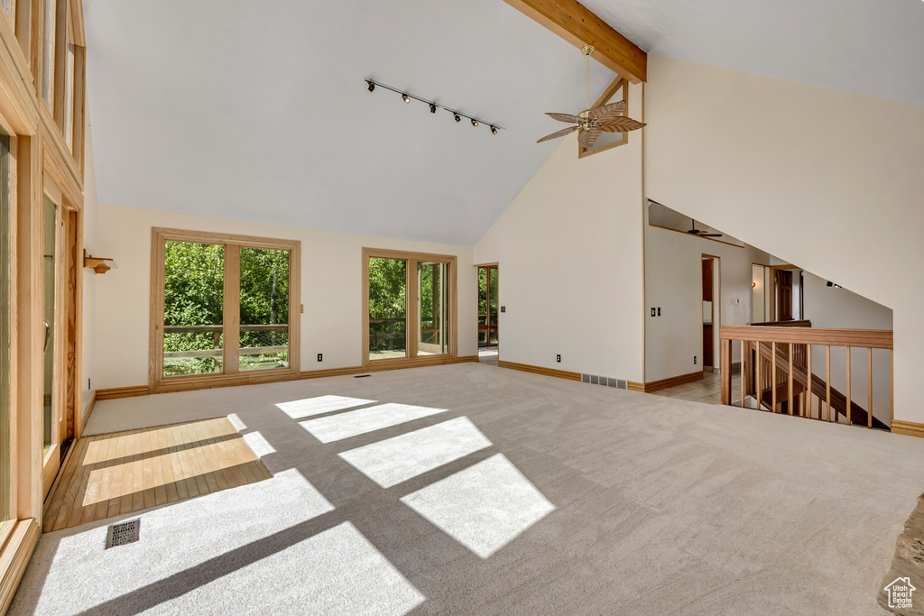 Unfurnished living room featuring rail lighting, a ceiling fan, high vaulted ceiling, and carpet