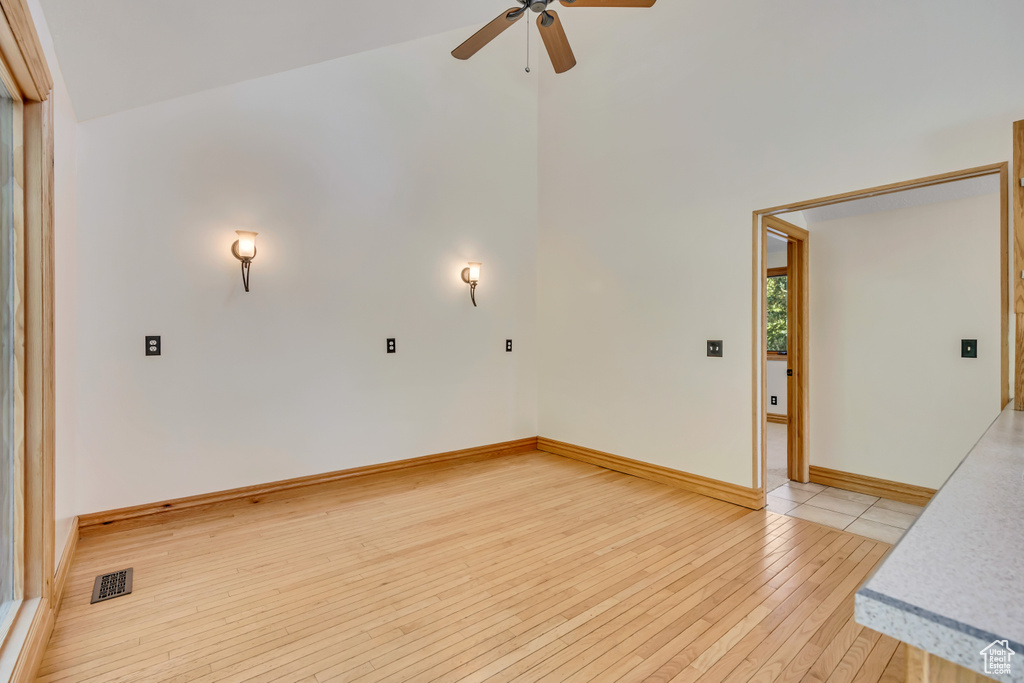 Unfurnished room with ceiling fan, light wood-type flooring, and high vaulted ceiling