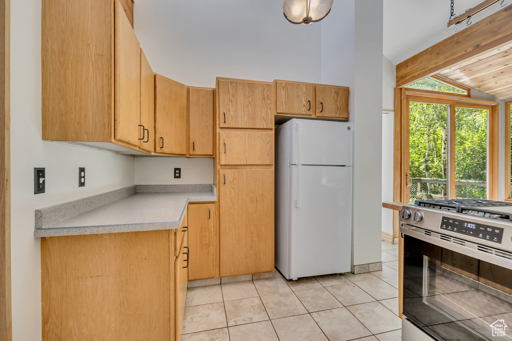 Kitchen featuring freestanding refrigerator, gas stove, light countertops, and light tile patterned floors