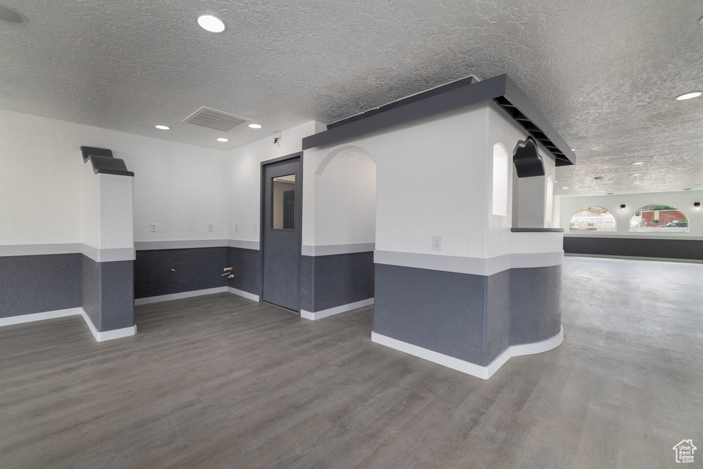 Empty room with a textured ceiling, wood finished floors, and recessed lighting