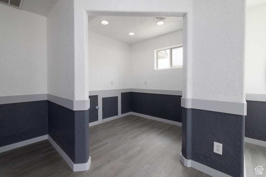 Unfurnished room featuring wood finished floors, a textured ceiling, and a textured wall