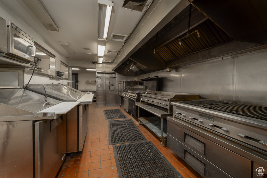 Kitchen with stainless steel microwave, tile patterned floors, and light countertops