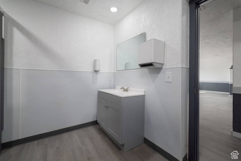 Bathroom with wood finished floors, vanity, a textured ceiling, and a textured wall