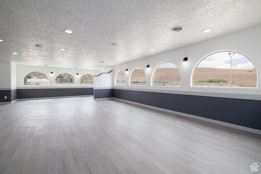 Unfurnished living room with a textured ceiling, recessed lighting, and wood finished floors