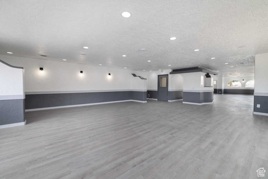 Unfurnished living room with recessed lighting, light wood-style floors, and a textured ceiling