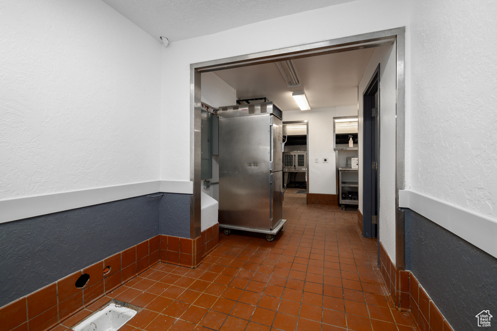Corridor with a textured wall and dark tile patterned flooring