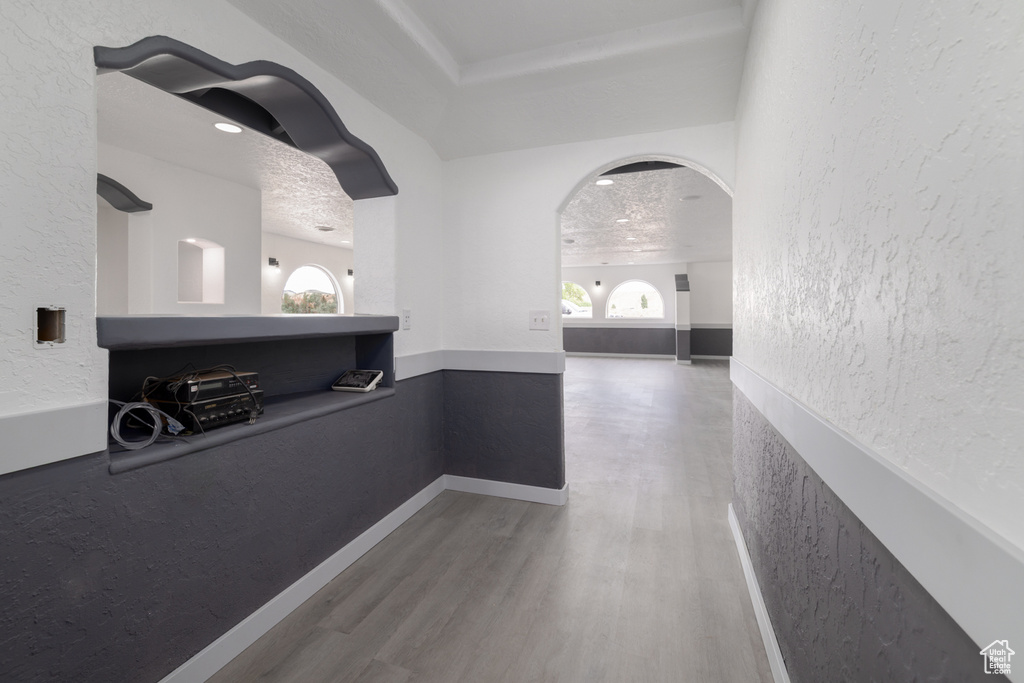 Hallway with wood finished floors, arched walkways, and a textured wall