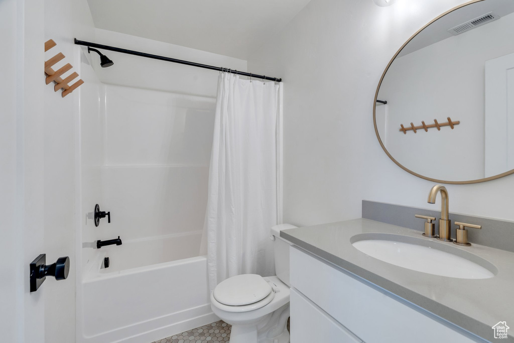 Bathroom featuring vanity, shower / bath combo with shower curtain, and tile patterned flooring