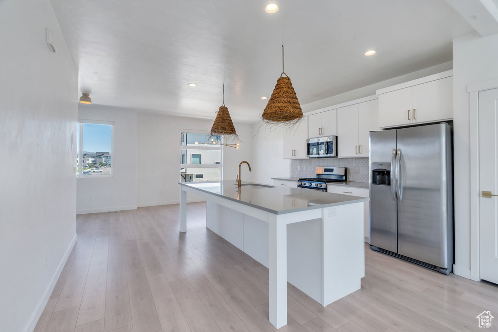 Kitchen with appliances with stainless steel finishes, a kitchen island with sink, decorative backsplash, white cabinetry, and recessed lighting