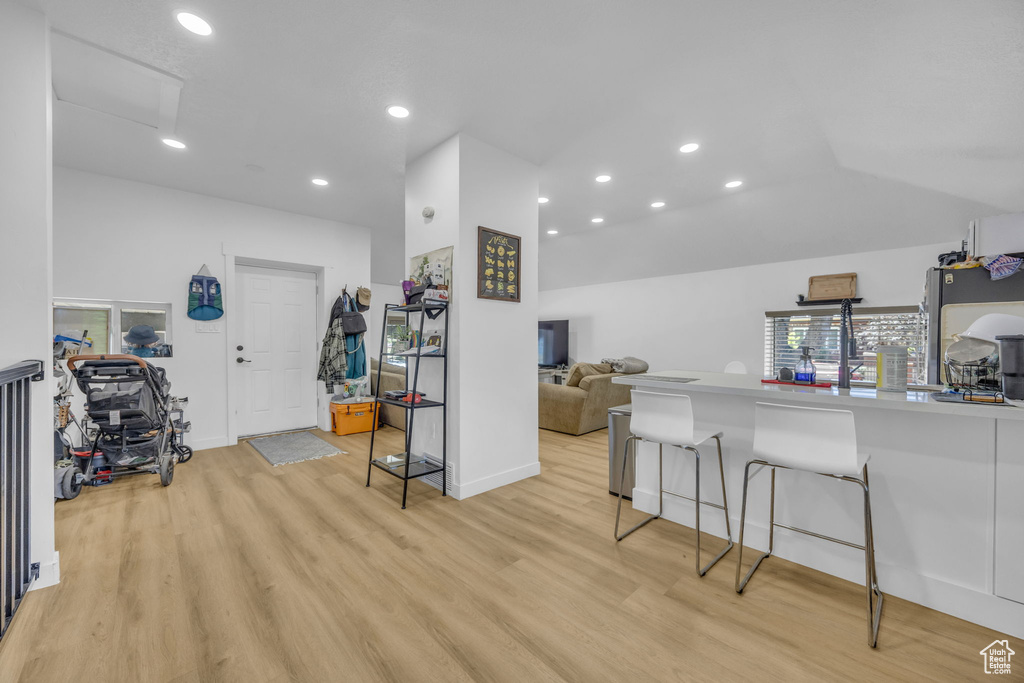 Kitchen featuring light wood-type flooring, a breakfast bar, recessed lighting, light countertops, and open floor plan
