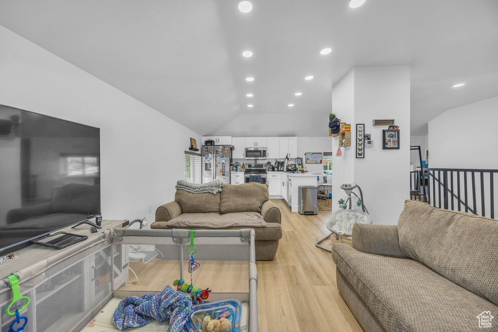 Living room featuring light wood finished floors, recessed lighting, and lofted ceiling