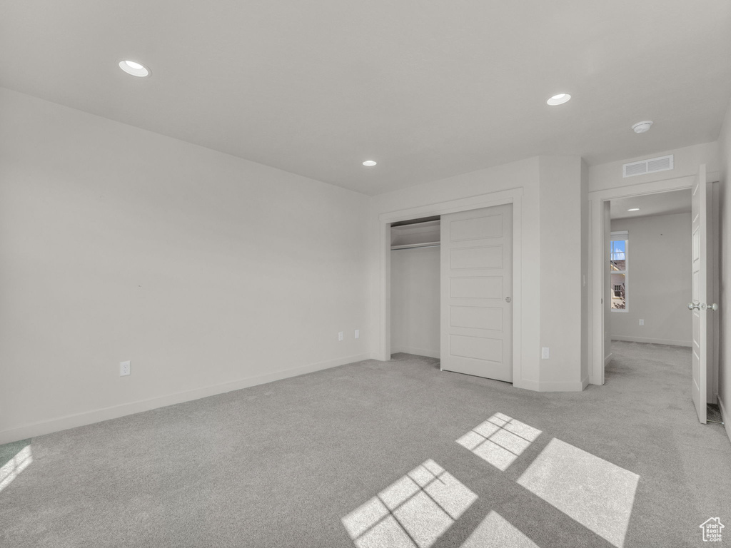 Unfurnished bedroom featuring light carpet, recessed lighting, and a closet