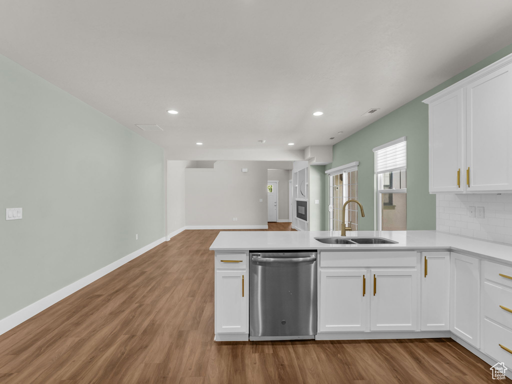 Kitchen with stainless steel dishwasher, wood finished floors, recessed lighting, light countertops, and white cabinets