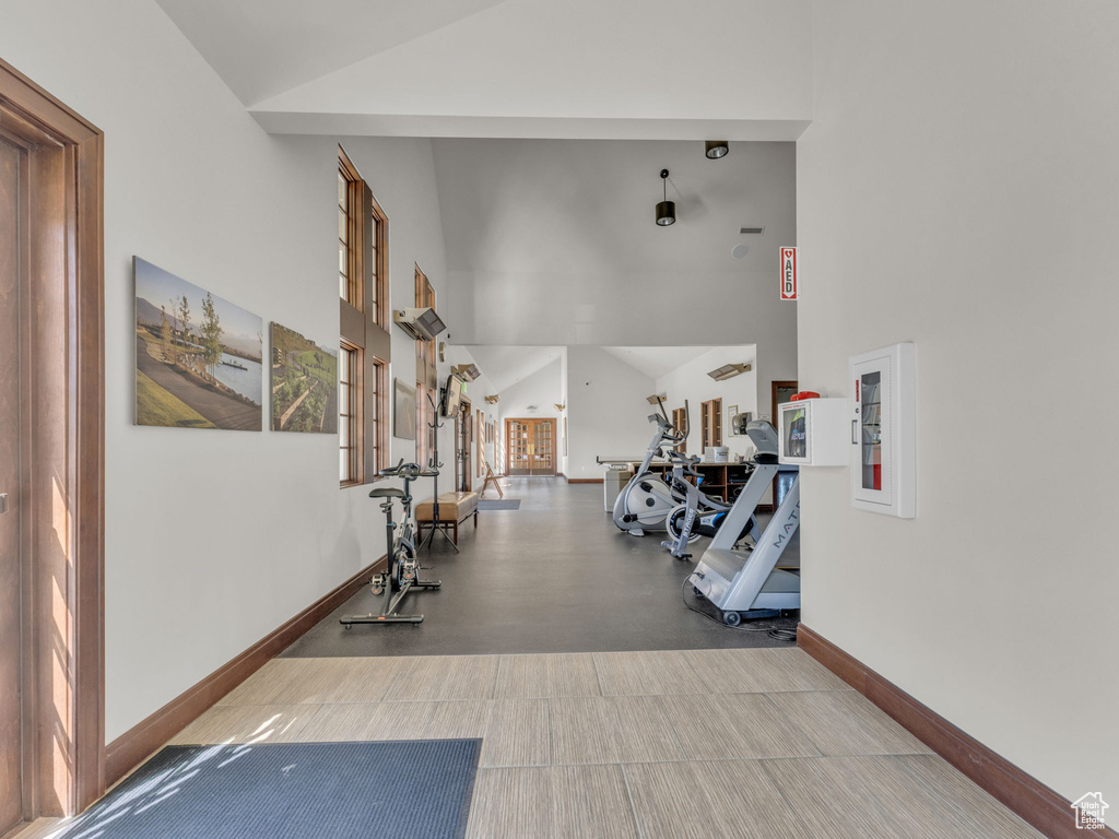 Exercise area featuring high vaulted ceiling and baseboards