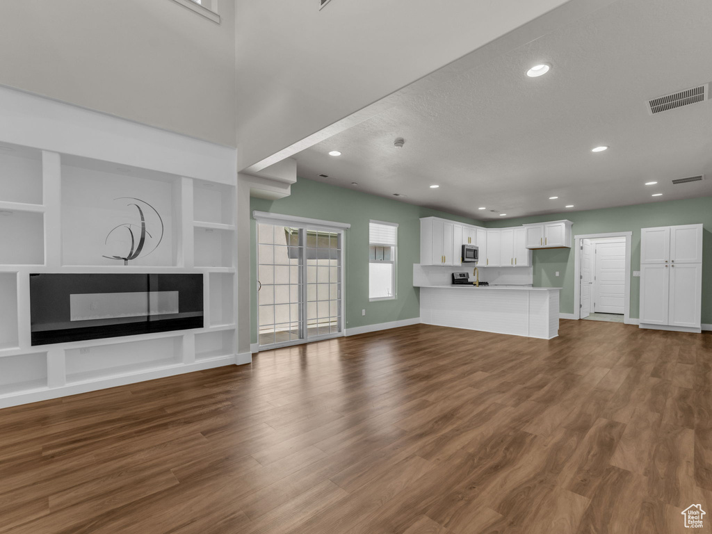 Unfurnished living room featuring recessed lighting, dark wood-type flooring, built in features, and a fireplace