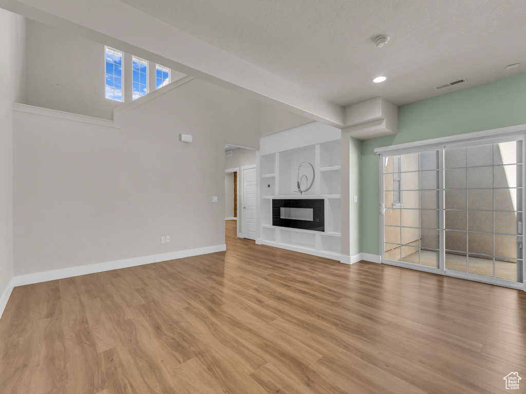 Unfurnished living room featuring light wood-type flooring, recessed lighting, healthy amount of natural light, and built in features