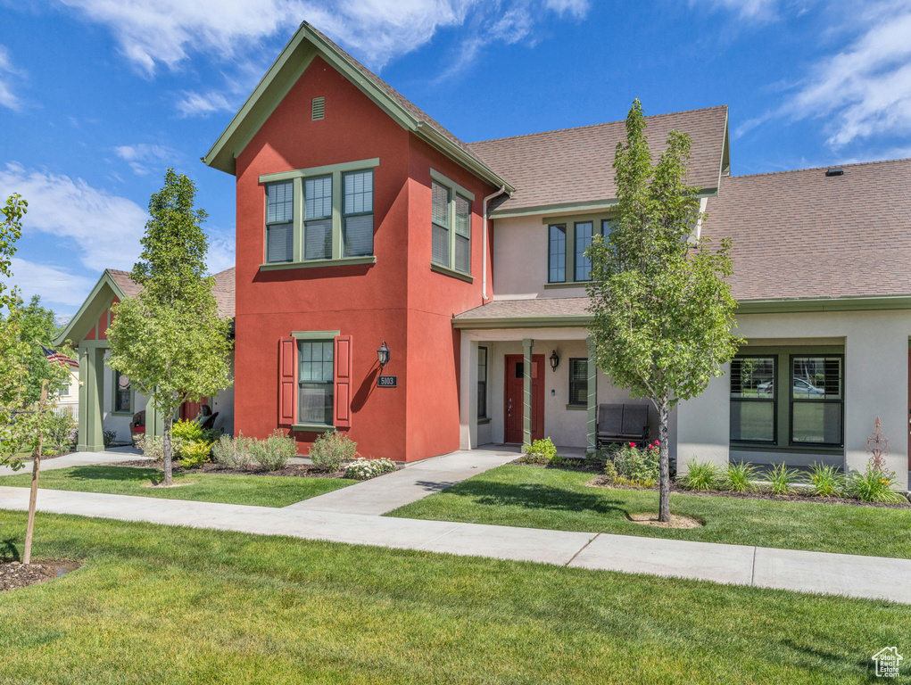 View of front of house featuring stucco siding, a front lawn, and roof with shingles