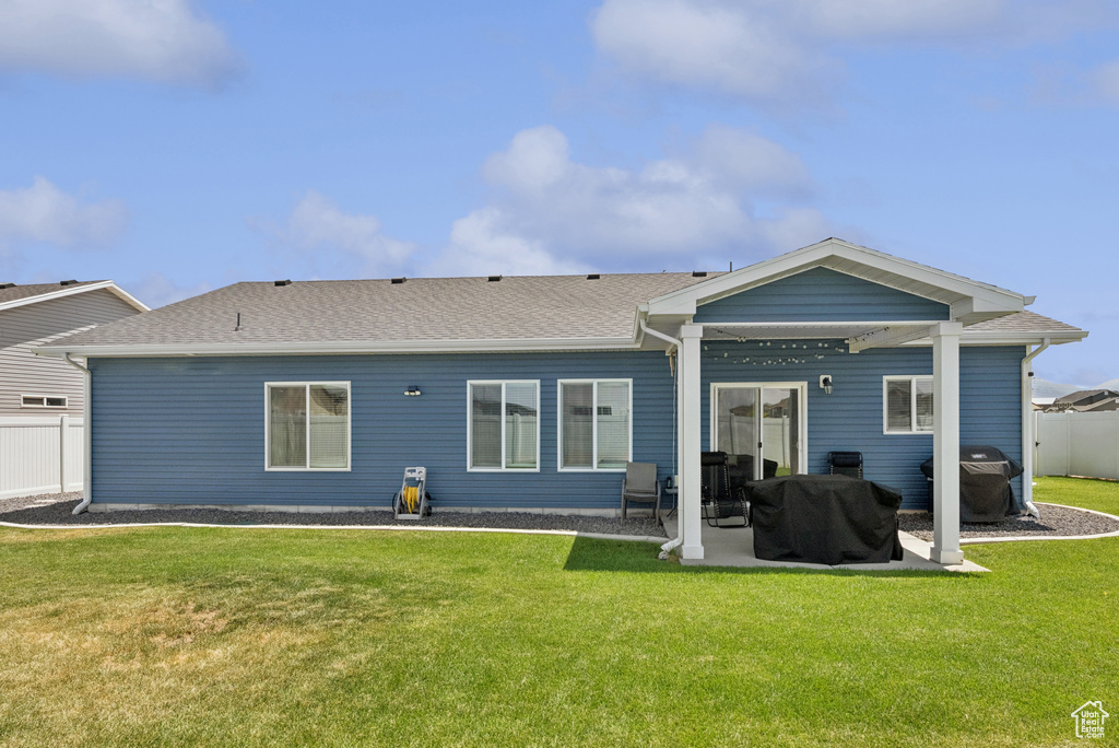 Rear view of house featuring a patio and a shingled roof