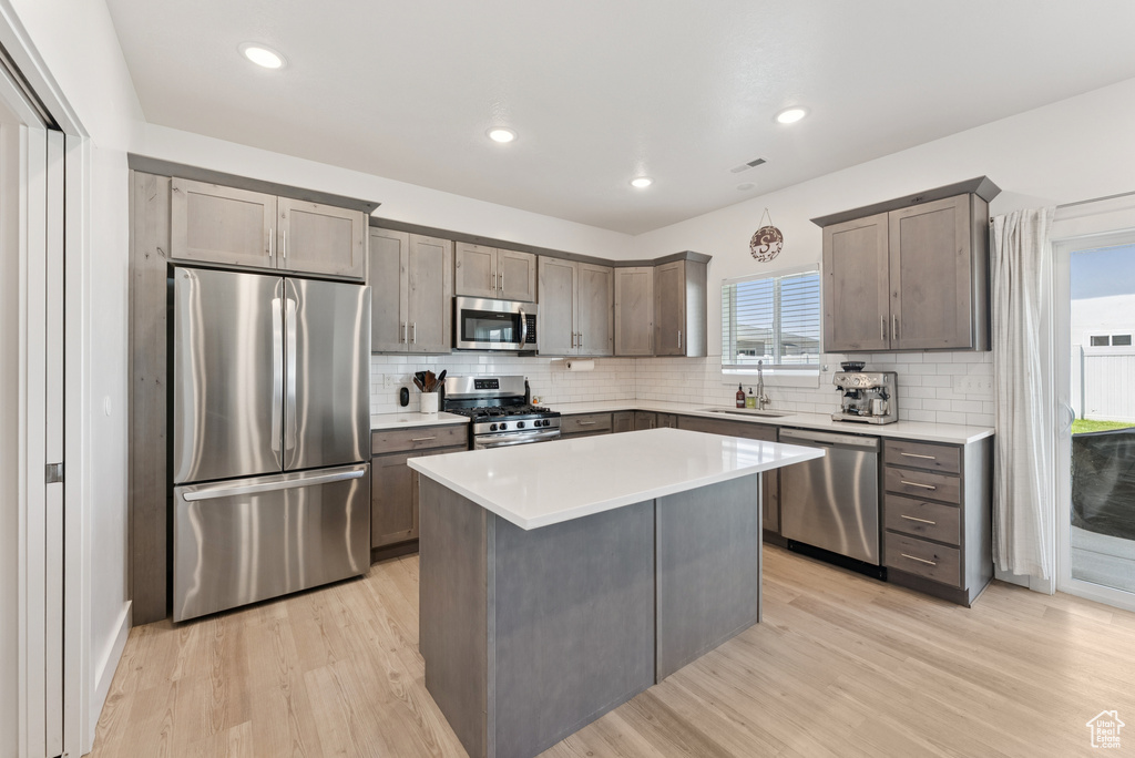 Kitchen featuring stainless steel appliances, light wood-style floors, tasteful backsplash, a kitchen island, and recessed lighting