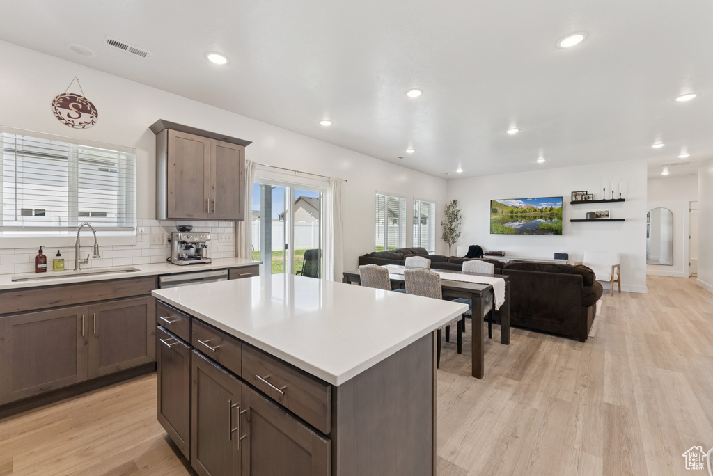 Kitchen with light wood finished floors, light countertops, tasteful backsplash, recessed lighting, and a kitchen island