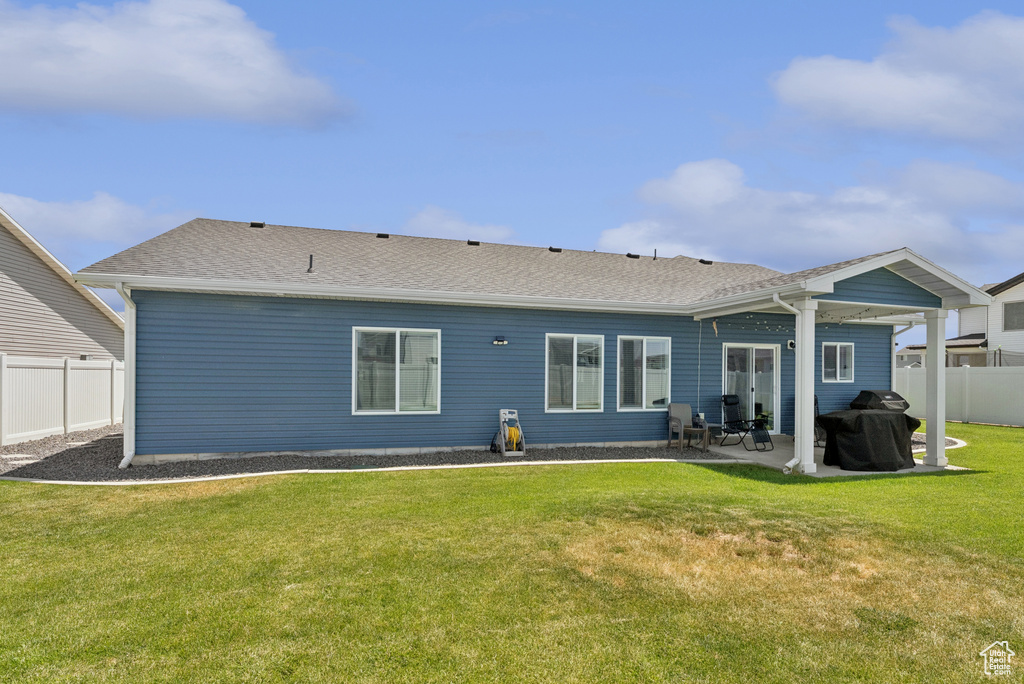 Rear view of house with a fenced backyard, a patio area, and roof with shingles