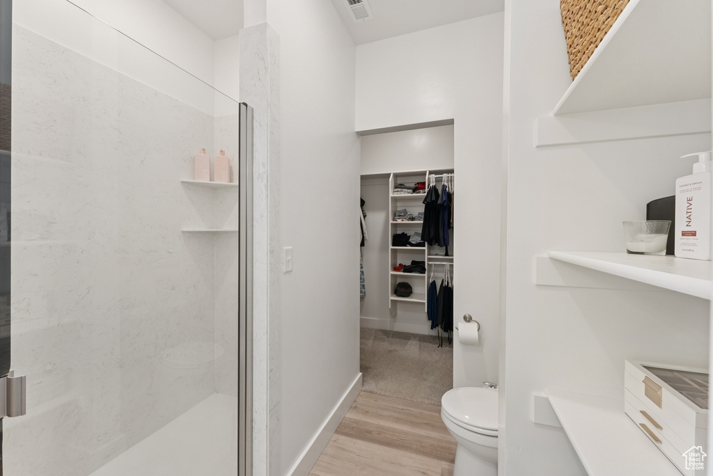 Full bath with a stall shower, wood finished floors, and a walk in closet