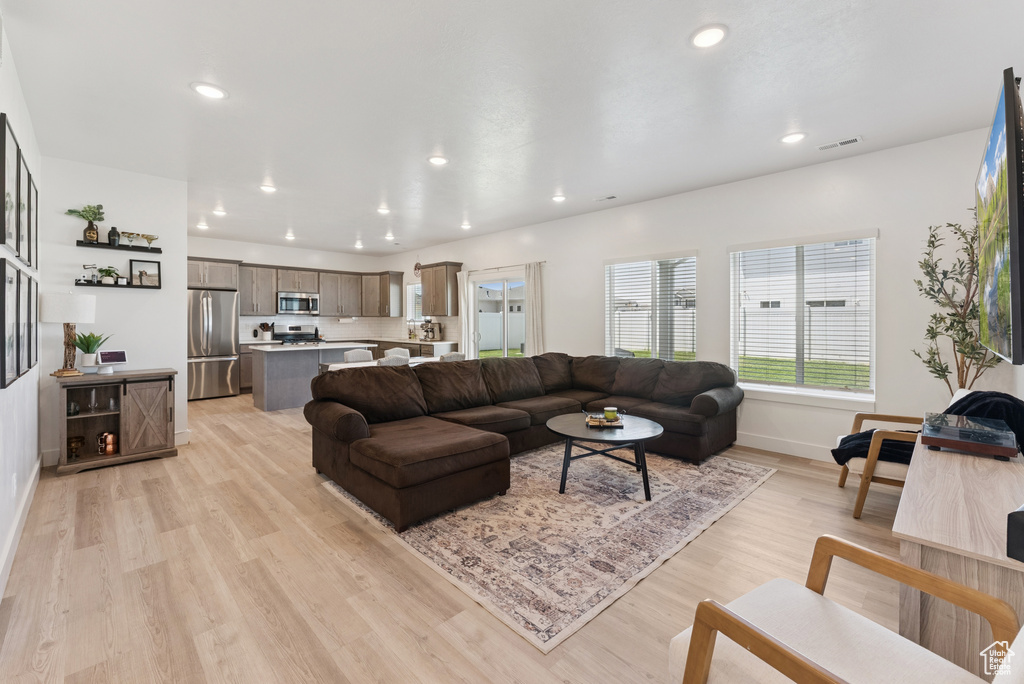 Living area with light wood-type flooring and recessed lighting