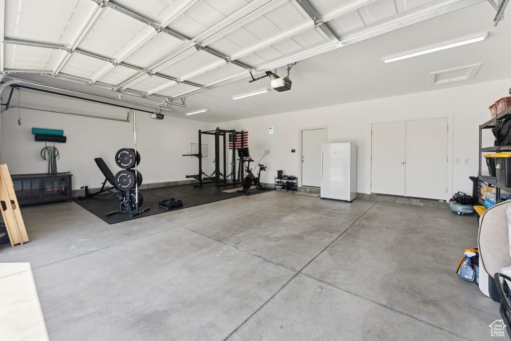 Garage featuring freestanding refrigerator and a garage door opener