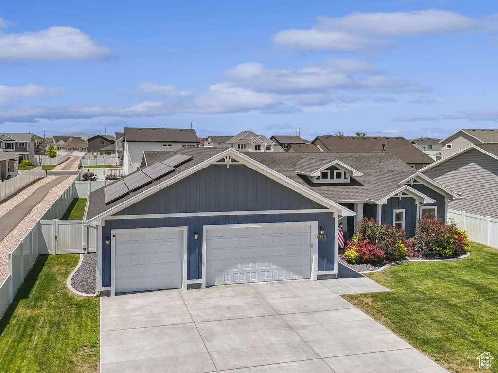 View of front of home with a residential view, driveway, solar panels, a fenced backyard, and a gate