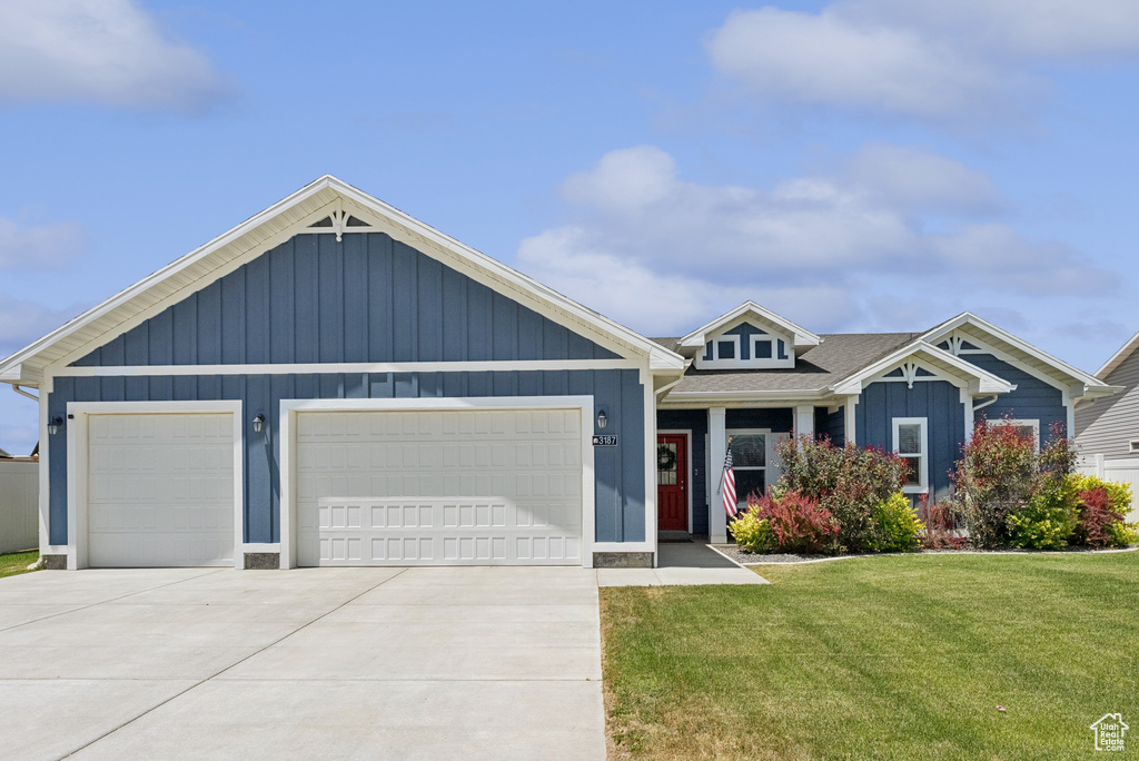 View of front facade with concrete driveway, a front lawn, an attached garage, board and batten siding, and a shingled roof