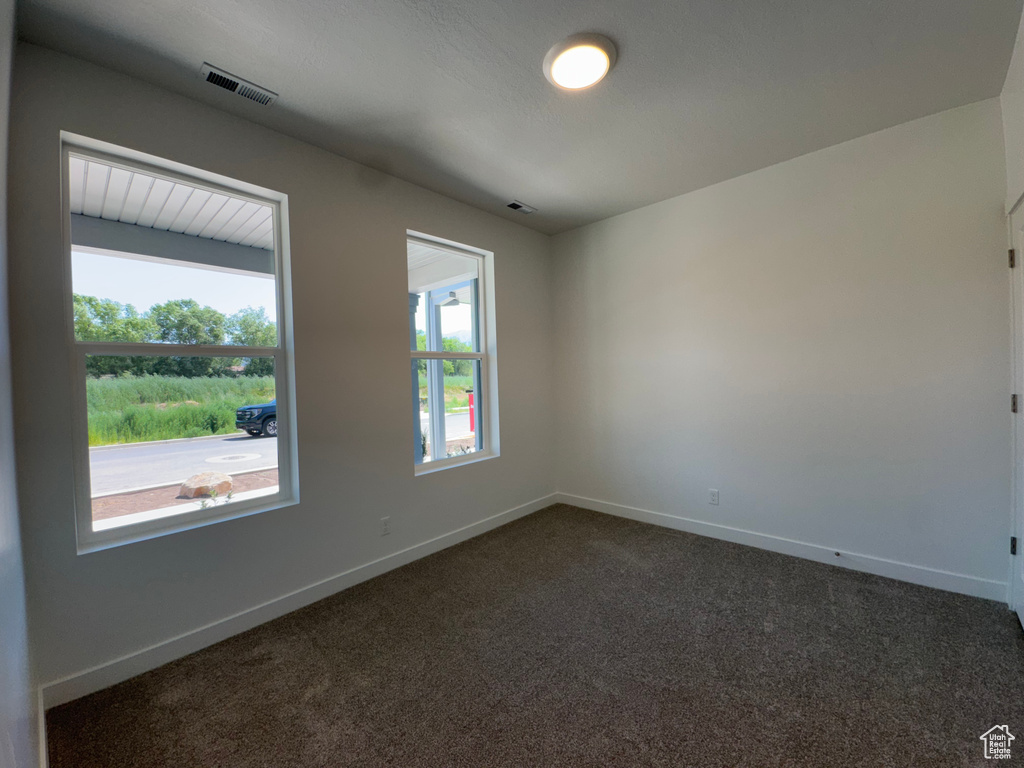 Spare room featuring dark colored carpet and baseboards