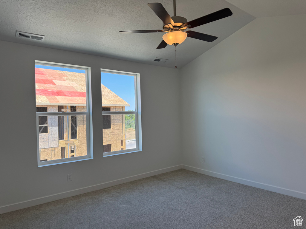 Carpeted spare room with ceiling fan and vaulted ceiling