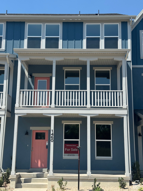 Townhome / multi-family property featuring a balcony, board and batten siding, and covered porch