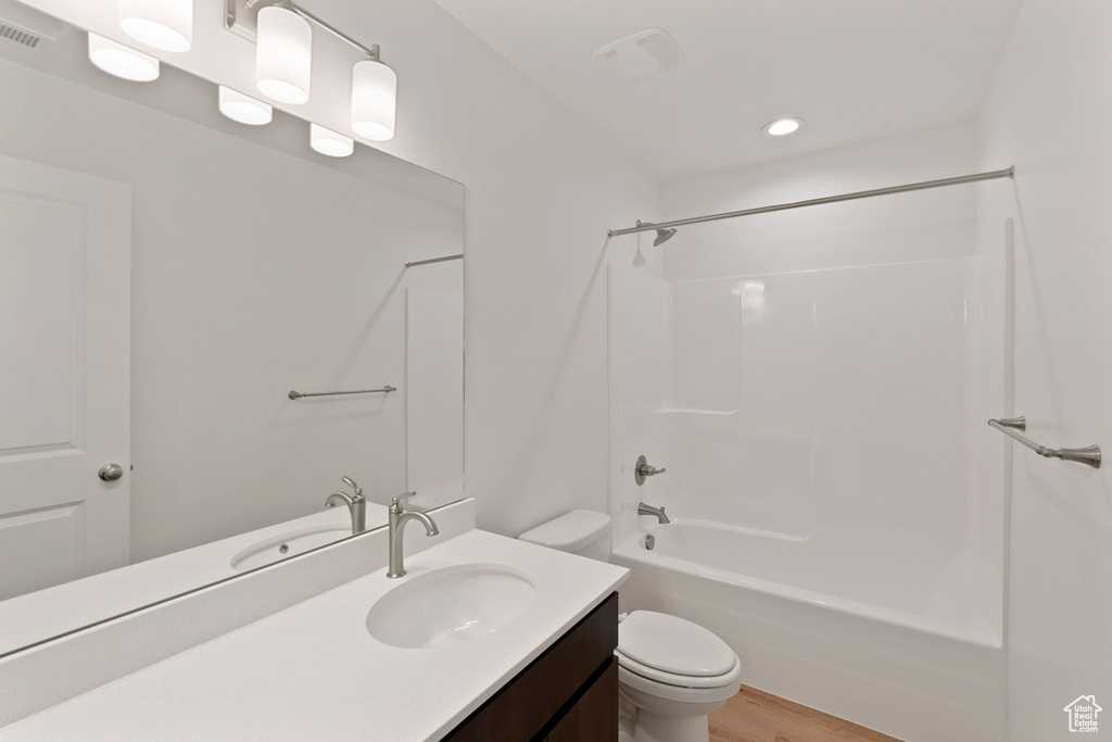 Full bath with vanity, shower / bath combination, wood finished floors, and recessed lighting