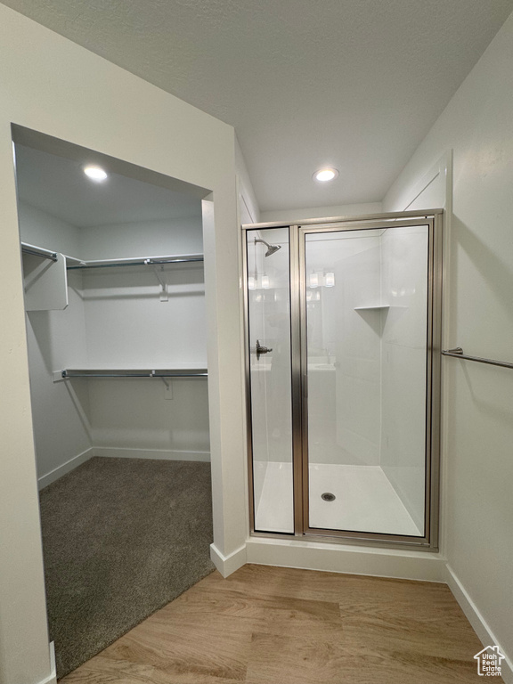 Full bathroom with a shower stall, a spacious closet, and recessed lighting