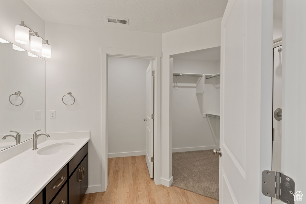 Full bath featuring vanity, wood finished floors, and a spacious closet