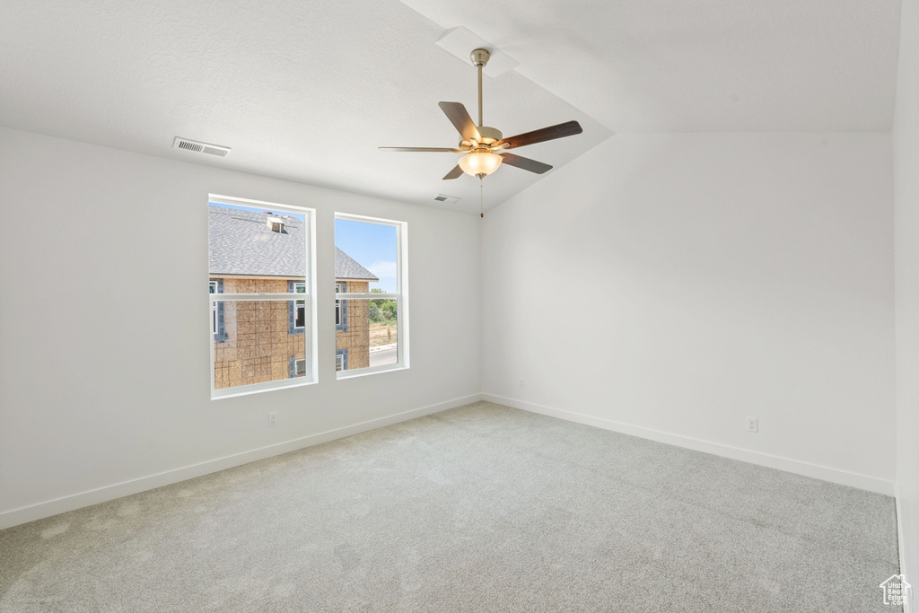 Spare room with carpet flooring, ceiling fan, and vaulted ceiling