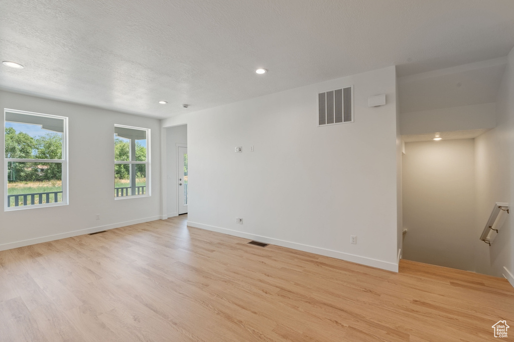 Empty room featuring light wood-style flooring, recessed lighting, and a textured ceiling