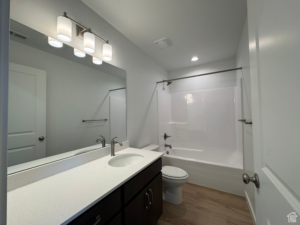 Full bath with vanity, wood finished floors, shower / washtub combination, and recessed lighting